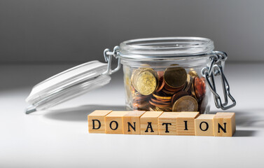 charity and financial help concept - close up of coins in glass jar for donation