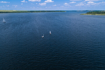 View from the air on the steppe river on a bright sunny day, on the river sailing boats. Sailing sports on the river.