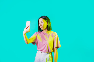 Young asiatic woman isolated using smartphone taking selfie