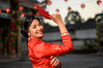 Asian beautiful woman wearing a cheongsam holding red envelope at shrine