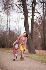 Fototapeta premium Beautiful young mother with her little daughter in park. Mother kissing her child outdoors. Family playing in autumn park.