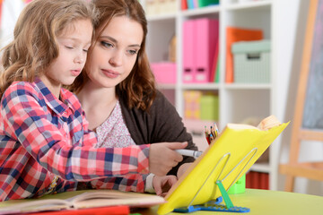 Cute little girl with her mother doing homework