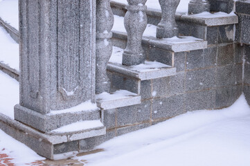 A close view of the granite steps under the snow. Balustrade stairs on the embankment on a winter...