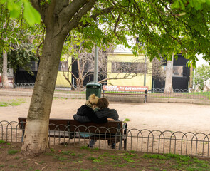 A loving couple on a bench under a tree