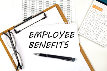 Text EMPLOYEE BENEFITS on the white paper on clipboard with chart and calculator