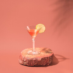 Red summer cocktail in a beautiful crystal glass on the pink draped silk background. Creative...