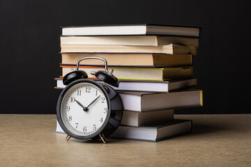 Naklejka premium Clock on the background of a stack of books