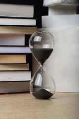 Hourglass on the background of books.