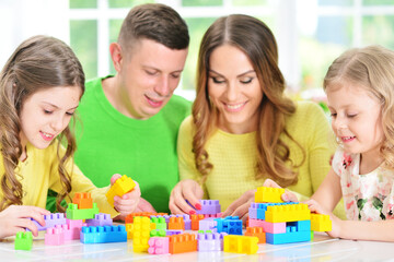Obraz na płótnie Canvas Girl with mother and father playing with colorful plastic blocks