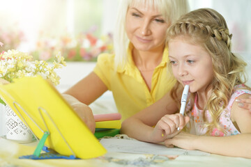 little cute girl with mother studying at home