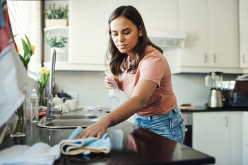 Keeping these countertops clean is a full time job. Shot of an attractive young woman using a cloth...