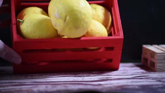 Lemons fall from a red wooden box