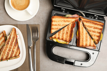 Modern grill maker with tasty sandwiches on light grey table, flat lay - obrazy, fototapety, plakaty