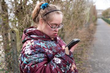Outdoor portrait of a 39 year old woman with the Down Syndrome, having a video call with her family