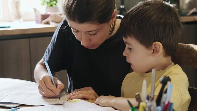 The mother showing the boy how to write each letter, the boy wanting to sneeze. Writing education concept. Child development. Education, school concept. School