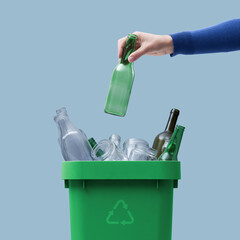 Woman putting a glass bottle in the trash bin