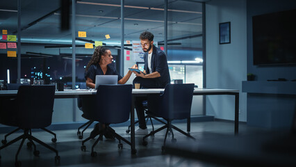 Obraz na płótnie Canvas Businesspeople in Modern Office: Business Meeting of Two Managers. Female CEO and Marketing Director Talk, Brainstorm Corporate Strategy, Implementing Marketing and Financial Plans. Evening Time.