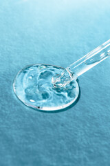Hyaluronic transparent gel with a glass dropper on a blue background, close-up front view.