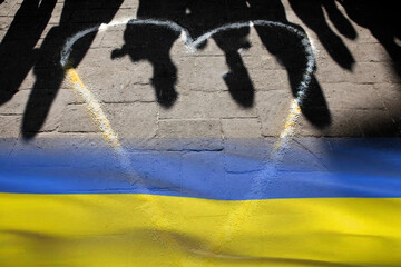 Ombre sul pavimento stradale e la bandiera dell'Ucraina - obrazy, fototapety, plakaty