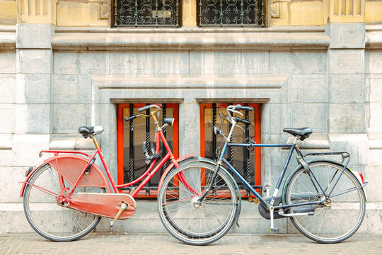 two symmetrical bicycles in front of two windows, in red and grey