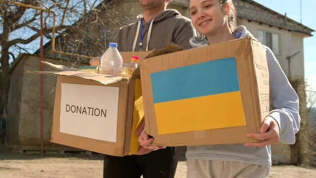 Close up video of volunteers carrying boxes with humanitarian aid for ukrainian refugees in street, charity campaign.