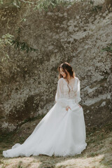 Fototapeta na wymiar beautiful bride stands on rocks in a glamorous white wedding dress