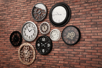 Collection of clocks hanging on red brick wall