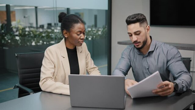 African female financial advisor businesswoman agent lawyer insurer colleague partner discuss project papers documents report with arab indian male explaining contract negotiating agreement consulting