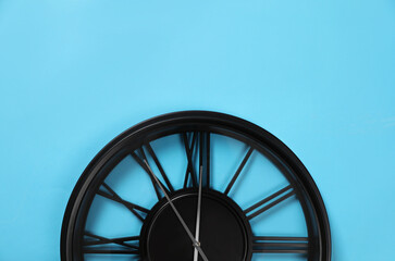 Stylish analog clock hanging on light blue wall, space for text. New Year countdown