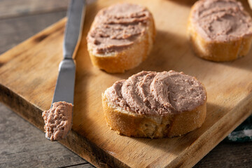 Toasted bread with pork liver pate on wooden table. Close up	