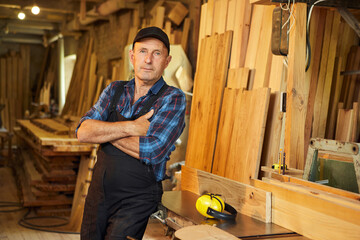 Portrait of Senior carpenter in uniform works on a woodworking machine at the carpentry...