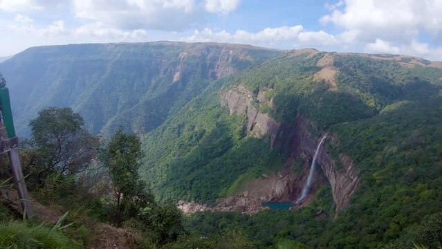 isolated waterfall falling from mountain top nestled in green forests from top angle