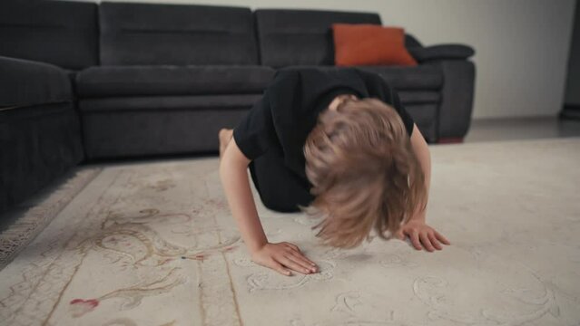 The boy is pushing up from the floor at home. Quarantine and sport concept. The child develops willpower and mode.