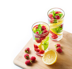 Detox fruits water with ice, raspberries, lemon, mint isolated on white background . Refreshing summer drinks, selective focus, above view