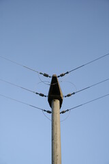 Torre de baja tensiòn en àngulo con sus conexiones de cables elèctricos sobre cremalleras para distribuciòn de luz en barrios, forma un diseño industrial con fondo de cielo azul - obrazy, fototapety, plakaty