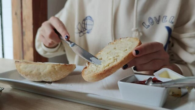 girl's hands spreading butter on white bread toast