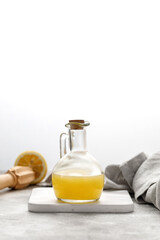 Glass bottle of freshly squeezed lemon juice, lemon squeezer and ripe lemons on grey background....