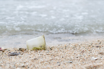 plastic cup on the beach, dirty sea