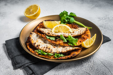 Turkish lahmacun pizza with mince meat and tomatoes on a plate with parsley and lemon. White background. Top view