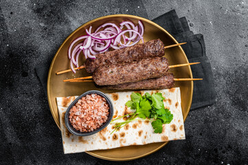 Lamb meat kofta kebab, onion and flat bread on plate. Black background. Top view - obrazy, fototapety, plakaty