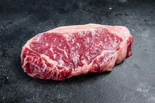 Raw Striploin steak, beef butchery cut. Black background. Top view