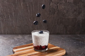 Chia seed pudding with yogurt, fresh blueberry in glass on dark stone table. Healthy breakfast. Clean eating and superfoods concept.