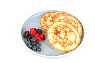 Pancakes with red fruits: blueberries, raspberries and blackberries on a white background 