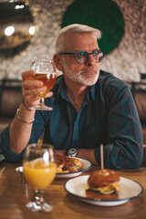 Leisure time of a mature man in a pub. The client of the bar has dinner and drinks beer after work.