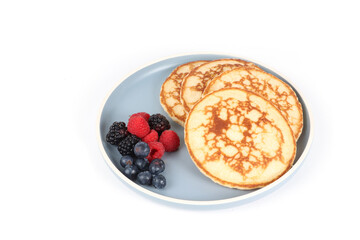 Pancakes with red fruits: blueberries, raspberries and blackberries on a white background 