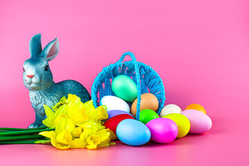 inverted basket with Easter eggs flowers and a rabbit on a pink background