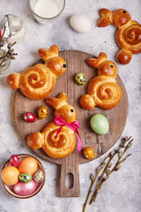 Buns made from yeast dough in a shape of Easter bunny, and colored eggs. Traditional Easter symbols and food.