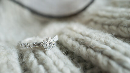 Close up of an elegant diamond ring on gray knit background. love and wedding concept. Soft and...
