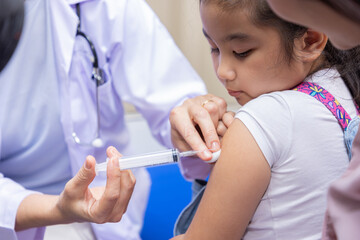 Young woman pediatrician performs a vaccination of a little girl. Looks at the doctor.