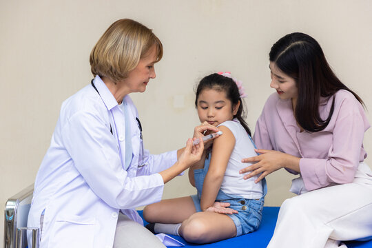 Young woman pediatrician performs a vaccination of a little girl. Looks at the doctor.